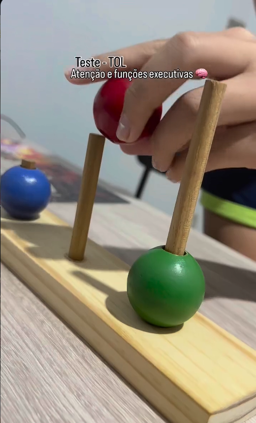 Mãos explorando uma atividade com peças coloridas e pinos de madeira